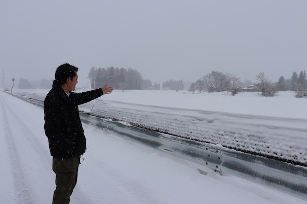 雪に覆われた圃場を案内する平井さん