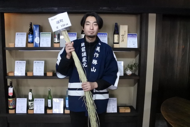 干した雄町の稲を持つ、代表取締役社長・辻総一郎さん