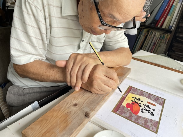 細かい字を面相筆で書く中山さん