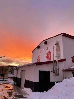 夕日を背景にした福司酒造の外観
